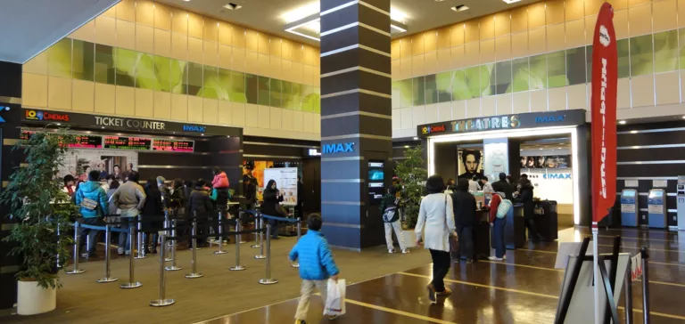Ingresso di un cinema con biglietteria e persone in attesa.